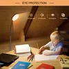 A young boy is doing homework at a desk under a floor lamp. Produktbild-Vorschau