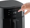 A hand is shown pressing a button on the digital display of a black air fryer. Produktbild-Vorschau
