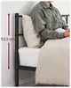 A person sitting on a bed with a metal bed frame. Náhled obrázku produktu