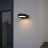 An outdoor wall light is mounted on a textured gray wall next to a dark window frame. Produktbild-Vorschau