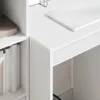 A close-up view of a white desk with a laptop on it and shelves with books. Produktbild-Vorschau