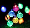 Nahaufnahme einer mehrfarbigen LED-Bubble-Lichterkette, die auf dunklem Gras hell leuchtet Produktbild-Vorschau