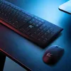 A black keyboard and mouse are placed on a dark, reflective surface with blue and red lighting. Produktbild-Vorschau