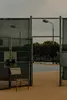 An open gate to a tennis court with a chair in the foreground. Produktbild-Vorschau