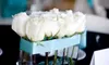 A close-up view of white roses in a glass vase adorned with a light blue ribbon. Náhled obrázku produktu