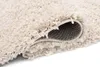 A close-up view of a beige rug, showing the texture of the fibers and the underside of the rug where it is rolled up. Náhľad obrázku produktu