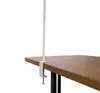 A white clamp-on stand attached to the edge of a wooden table. Produktbild-Vorschau