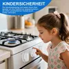 A young girl is looking at a gas stove with child safety locks on the knobs. Produktbild-Vorschau