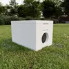 A white insulated cat house with a circular entrance sits on a grassy lawn. Náhled obrázku produktu