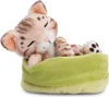 A plush toy cat sleeping in a green bed. Produktbild-Vorschau