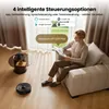 A man is sitting on a couch reading a book while a robot vacuum cleaner operates on the floor. Produktbild-Vorschau