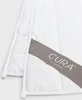 A close-up view of a white quilted blanket with a grey tag showing the brand name. Produktbild-Vorschau