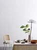 A table setting with a vase of dried flowers and greenery, a bowl, and cups, next to a chair with a fluffy throw. Produktbild-Vorschau