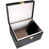 An open black box with a gold latch, lined with light gray fabric. A small black object is inside the box. Produktbild-Vorschau
