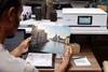 A person is holding a printed photo of Venice while sitting at a desk with a Canon printer in the background. Podgląd zdjęcia produktu