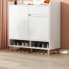A white shoe cabinet with wooden legs, filled with shoes. Náhľad obrázku produktu