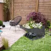 A robotic mower garage with flowers in a garden during a rain shower. Produktbild-Vorschau