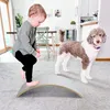 A toddler plays on a balance board next to a dog in a living room. Produktbild-Vorschau