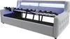 A light gray upholstered bed frame with the mattress support mechanism lifted to reveal storage space underneath. Blue LED lighting is visible behind the headboard. Voir les images du produit