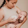 A woman is feeding a baby with a bottle. Anteprima dell’immagine prodotto