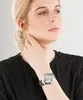 A woman wearing a black top and a silver watch on her wrist. Náhľad obrázku produktu