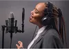 A woman wearing headphones and a suit jacket sings into a microphone in a recording studio. Podgląd zdjęcia produktu