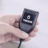 A hand holding a Trezor hardware wallet. Produktbild-Vorschau