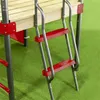 A close-up view of a metal playground ladder with red steps, attached to a wooden platform, on a green artificial turf surface. Produktbild-Vorschau