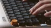 A close-up shot of a person's hands typing on a retro-style mechanical keyboard. Produktbild-Vorschau