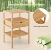 A bamboo nightstand with a drawer and shelves is shown in front of a blurred background of bamboo trees. Close-up views of the product's surface and stacked bamboo logs are also included. Náhled obrázku produktu