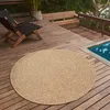 A round rug on a wooden deck next to a swimming pool. Náhled obrázku produktu
