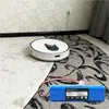 A robot vacuum cleaner is on a carpet next to a power outlet, with a replacement battery in the foreground. Produktbild-Vorschau