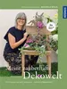 A woman is kneeling next to a wooden chair decorated with plants and a fairy figurine. The book cover is for "Meine zauberhafte Dekowelt". Náhľad obrázku produktu