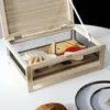 A wooden cheese cellar with various cheeses and crackers inside, displayed on a white surface. Voir les images du produit