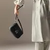 A person's hand holds a black handbag. Anteprima dell’immagine prodotto