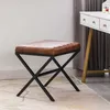 A brown leather-look stool with a black metal frame sits on a rug next to a white vanity table. Náhľad obrázku produktu