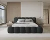 A modern bedroom with a large upholstered bed. Voir les images du produit