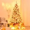 A decorated Christmas tree with presents underneath, in a cozy room setting with a chair and festive lights. Produktbild-Vorschau