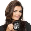 A woman holds a black mug with white text that says "HAVE A NICE DAY". Náhled obrázku produktu