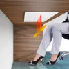 A person's legs are shown under a desk, with a white infrared heating panel mounted underneath the desk. Heat waves are depicted emanating from the panel. Voir les images du produit