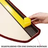 A hand is shown peeling off the protective backing from adhesive tape on the edge of a red and beige stair mat. Produktbild-Vorschau