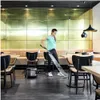 A woman is vacuuming the floor of a restaurant with a commercial vacuum cleaner. Produktbild-Vorschau