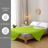 A green quilted blanket is spread on a bed in a bedroom setting. Produktbild-Vorschau