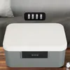 A lockable storage box with a combination lock is placed on a wooden surface, with a blurred background of a couch and pillows. Produktbild-Vorschau