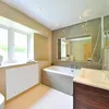 A modern bathroom with a bathtub, sink, and window. Voir les images du produit