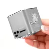 A hand is holding a small silver cube-shaped speaker. Produktbild-Vorschau