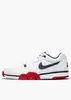 A side view of a white Nike Cross Trainer Low sports shoe with red and navy blue accents, set against a plain white background. Náhled obrázku produktu