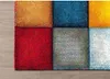 A close-up view of a colorful, checkered rug on a wooden floor. Produktbild-Vorschau