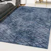 A blue geometric rug is shown in a living room setting, partially under a dark gray sofa. Produktbild-Vorschau