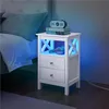 A white nightstand with blue LED lighting next to a bed. Produktbild-Vorschau